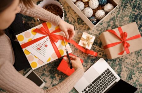 woman-wrapping-christmas-gift-while-sitting-carped-living-room_- custom printed tote bags --sustainable corporate gifts