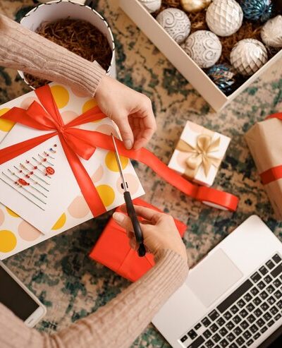 woman-wrapping-christmas-gift-while-sitting-carped-living-room_- custom printed tote bags --sustainable corporate gifts