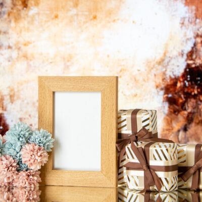 front-view-blank-picture-frame-holiday-presents-flowers-isolated-beige-abstract-background_-