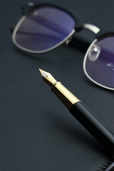 golden-pen-notebook-calculator-glasses-black-desk_-