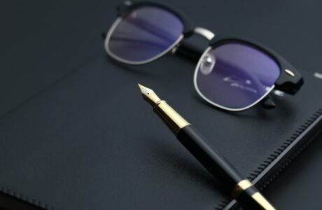 golden-pen-notebook-calculator-glasses-black-desk_-