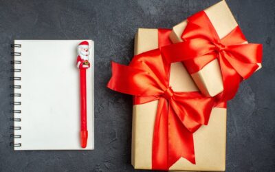view-christmas-background-with-beautiful-gifts-with-bow-shaped-ribbon-notebook-with-pen-dark-background_-