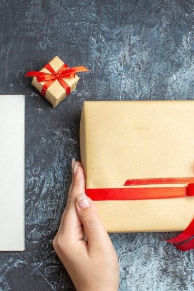 top-view-xmas-presents-tied-with-red-bows-notepad-light-dark-background_-